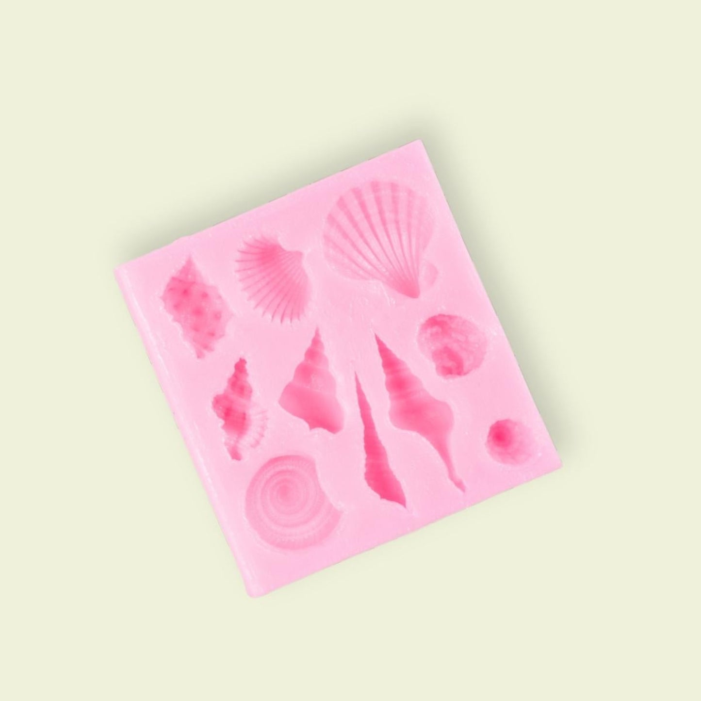 A pink silicone mold with various seashell shapes for food decoration.